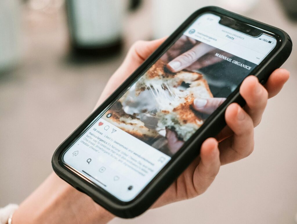 Woman's hand holding smartphone displaying social media content in close-up view.